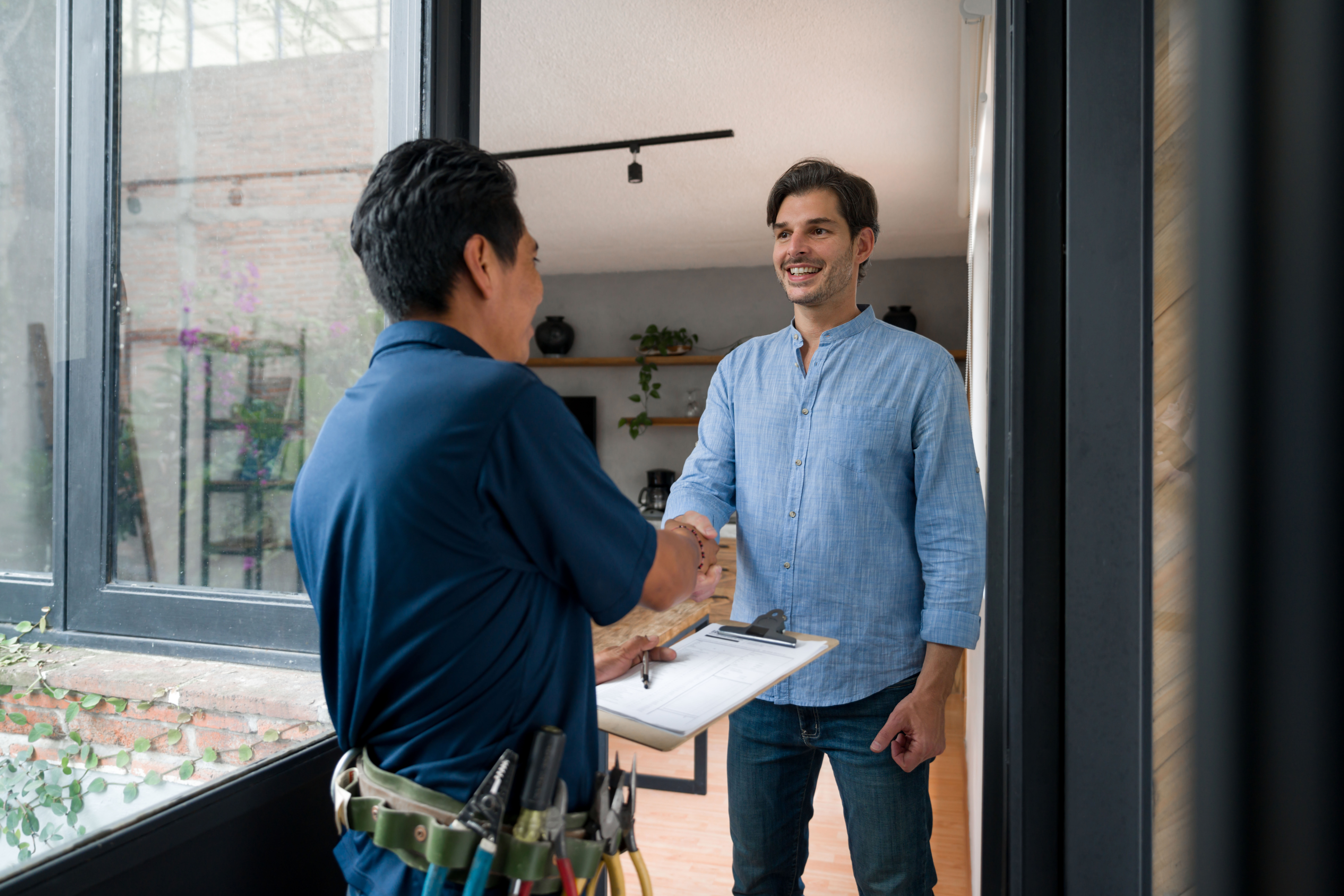 HVAC tech greeting a client with a handshake at the door of his house